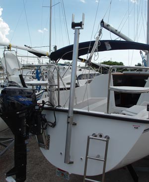 A mast support crutch with roller on a different Precision 23. The support can be extended for easier mast raising and lowering, then retracted for a lower profile when trailering the boat. On this prototype we discovered that it is important to install blocks on the pintel/gudgeon arrangement to prevent the whole pole from rotating. The roller works well when walking the mast forward and back from the step to its trailering position, but it only works well when it is aligned with the mast. Pintles and gudgeons are designed to make rudders easy to turn, and they make the pole much too easy to misalign.